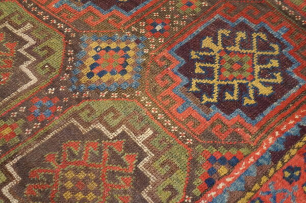 Detailed view of a multicolored geometric rug pattern featuring red, blue, green, yellow, and deep brown.
