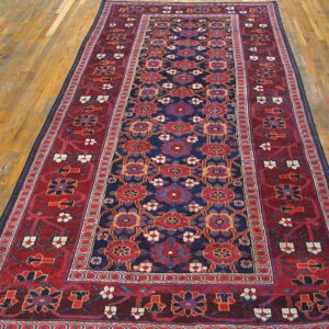 Navy blue and deep red runner rug with repeating geometric medallions sits on golden hardwood flooring.