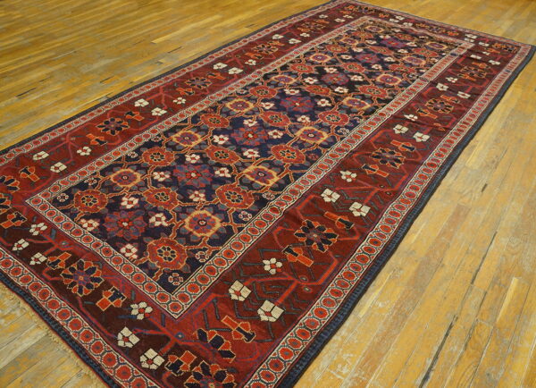 Red and navy traditional runner rug displayed on wide plank, yellow-toned hardwood floors.