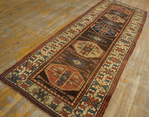 Dark brown runner with large geometric medallions and a patterned border rests on distressed yellow wood floorboards.