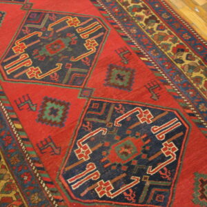 Traditional red rug with blue geometric patterns and multi-colored borders visible on a wood floor.