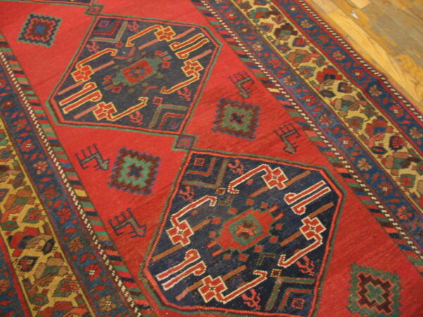 Traditional red rug with blue geometric patterns and multi-colored borders visible on a wood floor.