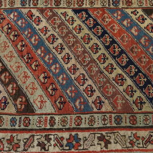 Diagonal stripes of terracotta, navy, and beige cover this rug section, framed by detailed geometric borders.