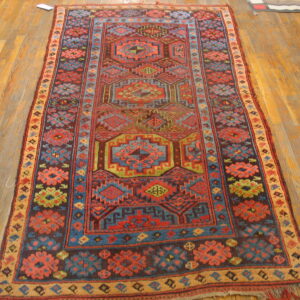 Tribal geometric runner rug with red, blue, green, and brown patterns lying on a natural wood floor.