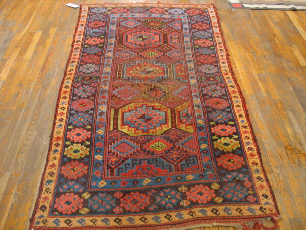 Tribal geometric runner rug with red, blue, green, and brown patterns lying on a natural wood floor.