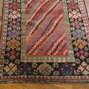 High-pile rug with a multicolored diagonal pattern and geometric borders rests on light wood planks.