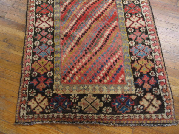 High-pile rug with a multicolored diagonal pattern and geometric borders rests on light wood planks.