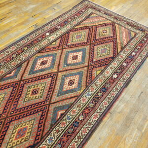 Red and dark blue geometric runner rug with complex borders lying on rustic wooden planks.