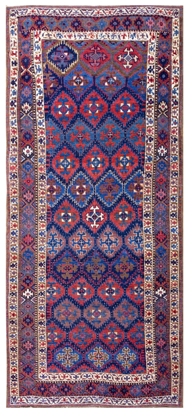 A narrow rug featuring geometric medallions in red and blue on a dark blue field with intricate borders.