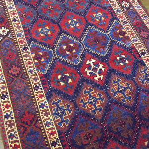 Close-up of a deep red and navy blue geometric rug runner on natural wood plank flooring.
