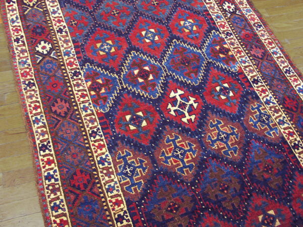 Close-up of a deep red and navy blue geometric rug runner on natural wood plank flooring.