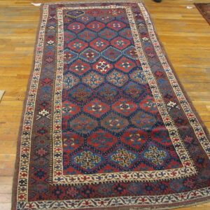 Low pile runner rug featuring red, navy, and brown geometric diamonds on a light wood floor.