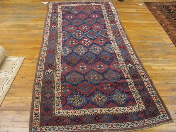 Low pile runner rug featuring red, navy, and brown geometric diamonds on a light wood floor.