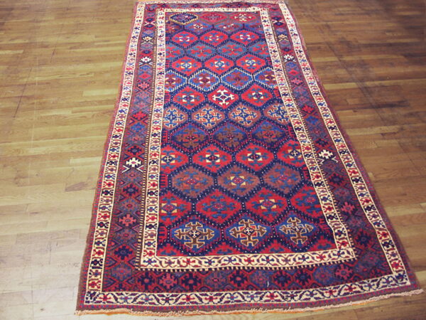 Red and blue geometric runner rug with complex borders laid over light wood planks.