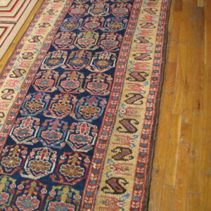 Colorful blue and red traditional runner and a geometric rug are laid on light brown wooden floors.