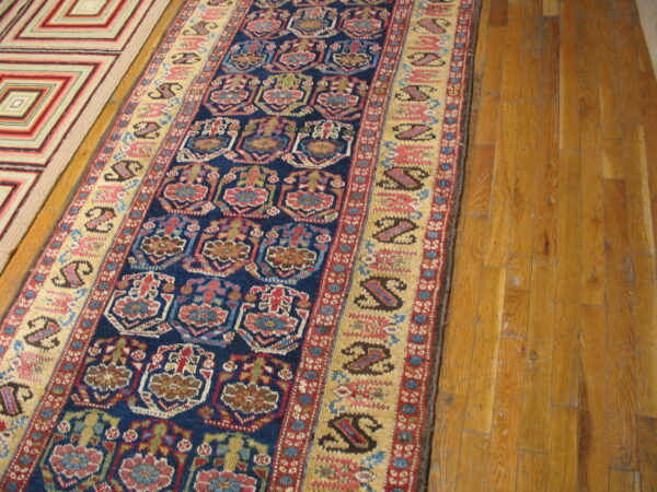 Colorful blue and red traditional runner and a geometric rug are laid on light brown wooden floors.