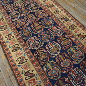 Deep blue runner with colorful geometric designs and wide paisley borders sits on rustic wood planks.