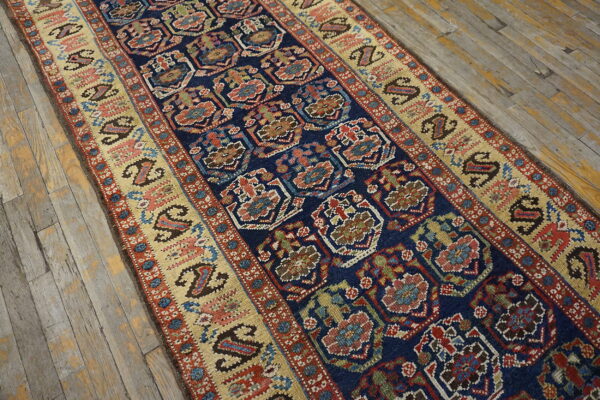 Deep blue runner with colorful geometric designs and wide paisley borders sits on rustic wood planks.