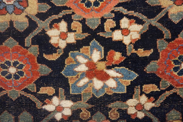 Navy blue rug detail with dense floral patterns in terracotta, cream, light blue, and sage green.