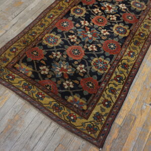 A navy rug with dense red, blue, and gold floral patterns lies diagonally on distressed wooden planks.