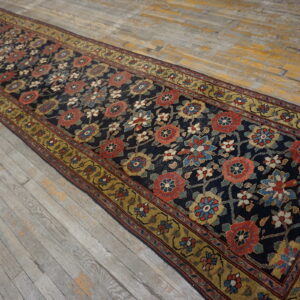 Dark blue floral runner rug with rust and gold accents laid over distressed wood floor.