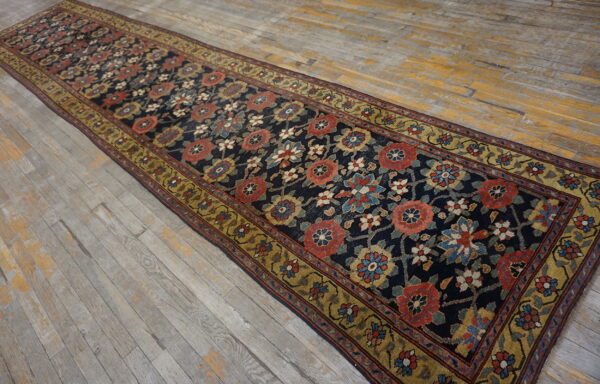 Dark blue floral runner rug with rust and gold accents laid over distressed wood floor.