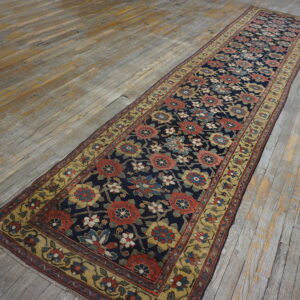 Navy runner with dense floral pattern and wide gold border lies on weathered gray plank flooring.