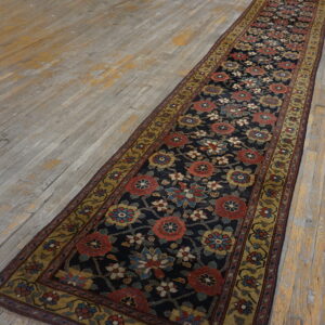 Navy floral runner with red and gold motifs lies on a distressed gray and yellow wood floor.