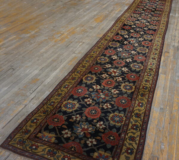Navy floral runner with red and gold motifs lies on a distressed gray and yellow wood floor.
