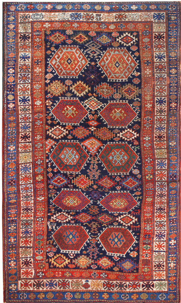 Navy blue rug with repeating red, orange, and teal geometric medallions and a complex tribal border.