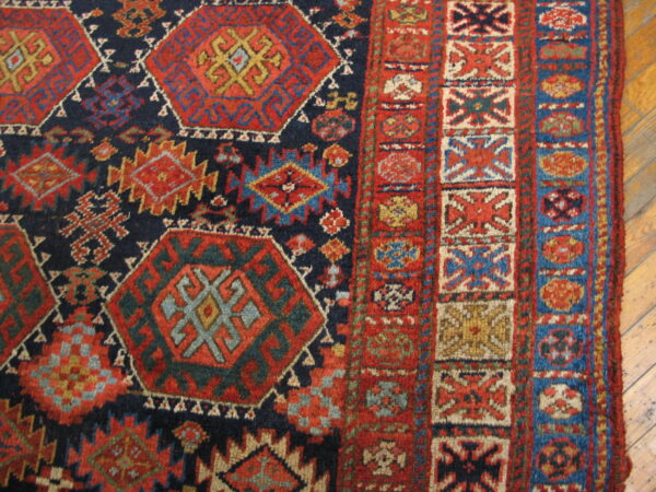 Highly patterned rug with red and gold octagons, thick borders, and visible low pile on hardwood.