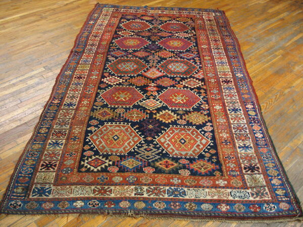 Dark geometric runner rug with red, orange, and blue medallions rests on light wood plank flooring.