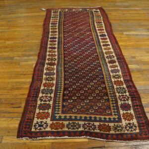 Geometric red and blue runner rug with diamond lattice and medallion borders on a wood floor.