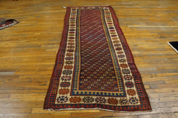 Geometric red and blue runner rug with diamond lattice and medallion borders on a wood floor.