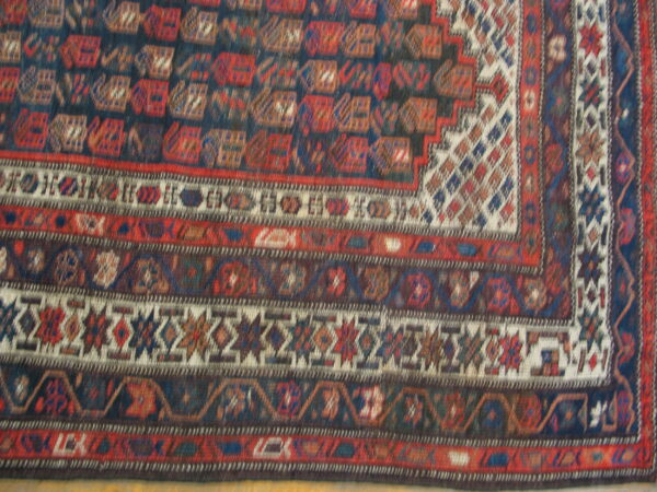 Geometric rug detail showing multiple borders in dark blue, deep red, and cream intricate patterns.