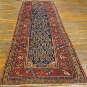 Traditional runner rug featuring a blue hexagonal pattern and wide rust red borders on wood floor.