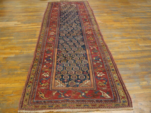 Traditional runner rug featuring a blue hexagonal pattern and wide rust red borders on wood floor.