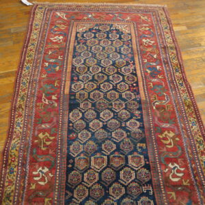 Navy runner with geometric medallions and wide rust border rests on natural wood flooring.