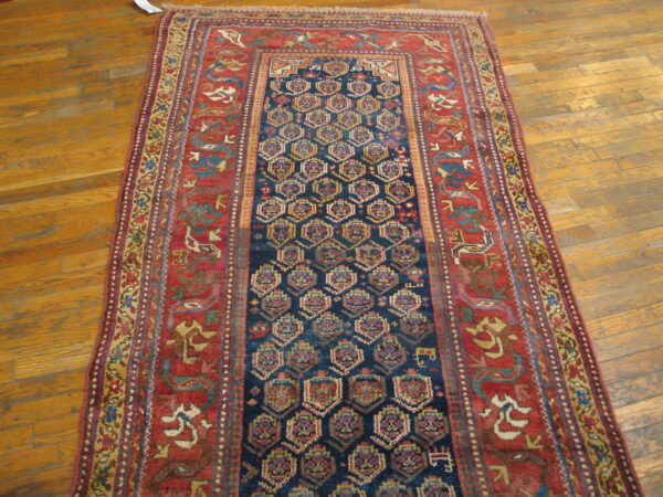 Navy runner with geometric medallions and wide rust border rests on natural wood flooring.
