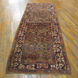 Detailed traditional runner in mossy green, red, and blue geometric patterns rests on glossy hardwood flooring.