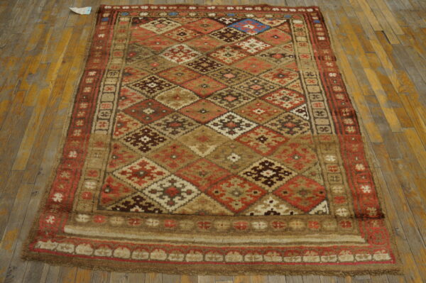 Geometric diamond rug in warm tones of brown, red, and tan resting on light wooden planks.