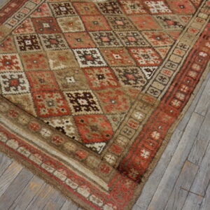 Geometric high-pile rug in rust, brown, and cream tones resting on weathered wood planks.
