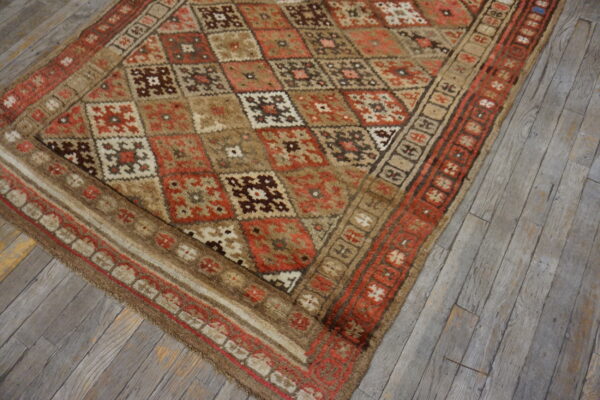 Geometric high-pile rug in rust, brown, and cream tones resting on weathered wood planks.