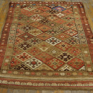 Shaggy, rustic rug with geometric diamonds in tan, brown, and red on worn wood flooring.