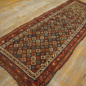 Red, blue, and tan runner featuring complex borders and a central geometric field on rustic wooden planks.