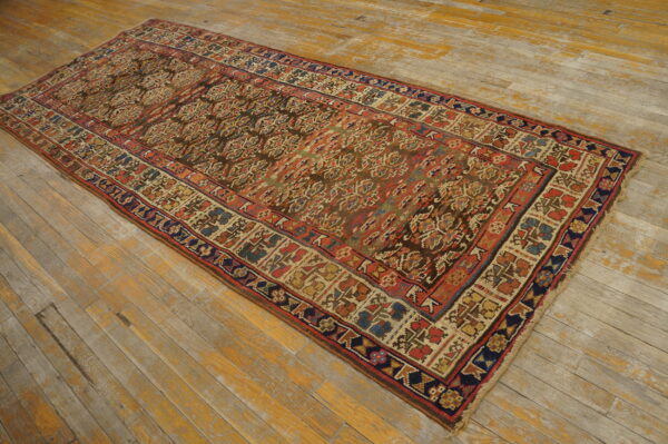 Low-pile runner rug featuring complex red, blue, and brown geometric patterns on distressed wood flooring.