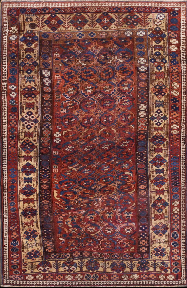 Red and blue tribal rug with dense geometric patterns and complex tan and maroon multi-layered borders.