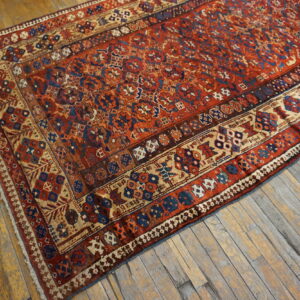 Red, blue, and tan geometric patterned low-pile rug on rustic wooden plank floors.