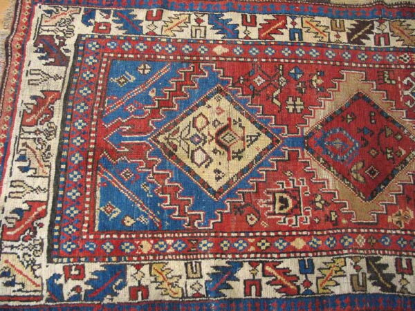 Close-up of a traditional geometric rug with primary red, blue, and cream diamond patterns.