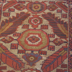 Flatweave rug detail showing a central diamond motif with geometric patterns in red, beige, and blue.